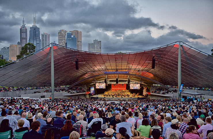 People sitting in front of a massive open-air music stage.